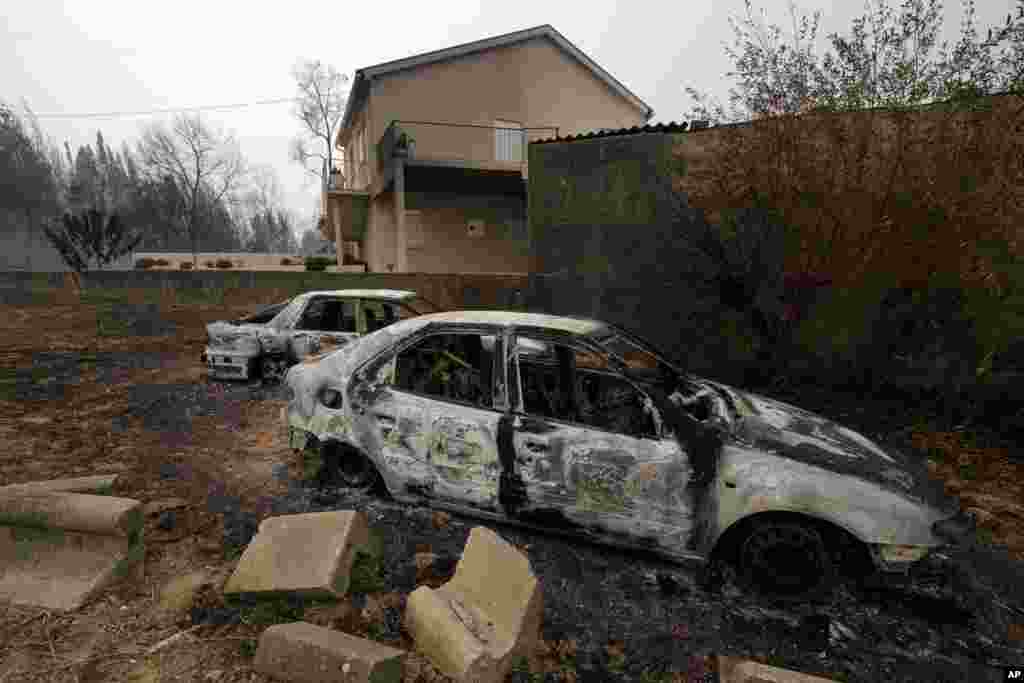 Burnt cars are seen next to a house near Penacova, northern Portugal. Wildfires killed at least 27 people, injured dozens more and left an unconfirmed number of missing in the country's second such tragedy in four months, officials said.