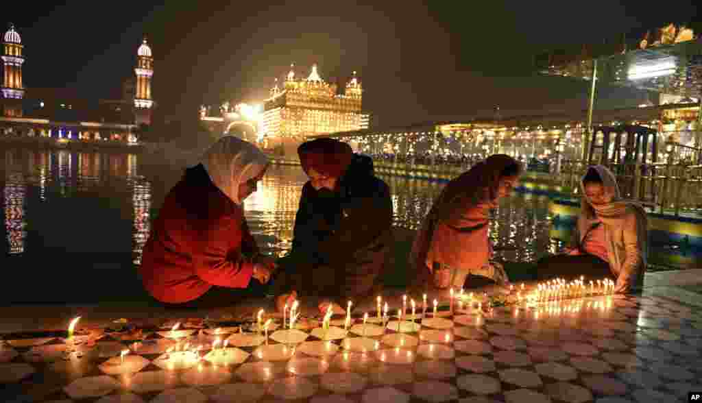 Sikh devotees light candles in the pre-dawn hours at the illuminated Golden Temple, the holiest of Sikh shrines, during the birth anniversary of Guru Nanak, the first Sikh Guru, in Amritsar, India.