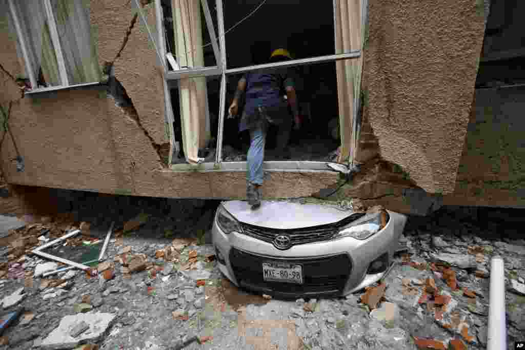Rodrigo Diaz Mejia climbs over a crushed car into what was a second-story apartment at 517 Tokio street, collapsed by the earthquake almost one month ago in the Portales Norte neighborhood of Mexico City, Oct. 18, 2017.
