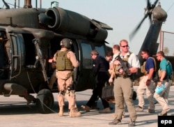 Iraq -- US administrator Paul Bremer (C) is guarded by private US security company personnel while he boarded a helicopter in the Iraqi city of Hillah, June 17, 2007
