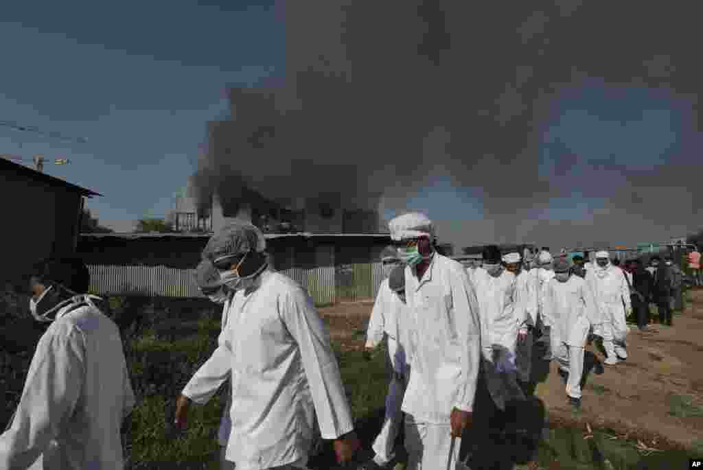 Employees leave as smoke rises from a fire at Serum Institute of India, the world's largest vaccine maker that is manufacturing the AstraZeneca/Oxford University vaccine for the coronavirus, in Pune, India.