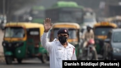 A traffic policeman wears a mask to protect himself from air pollution at a junction during restrictions on private vehicles based on registration plates, on a smoggy morning in New Delhi, India, November 4, 2019. REUTERS/Danish Siddiqui