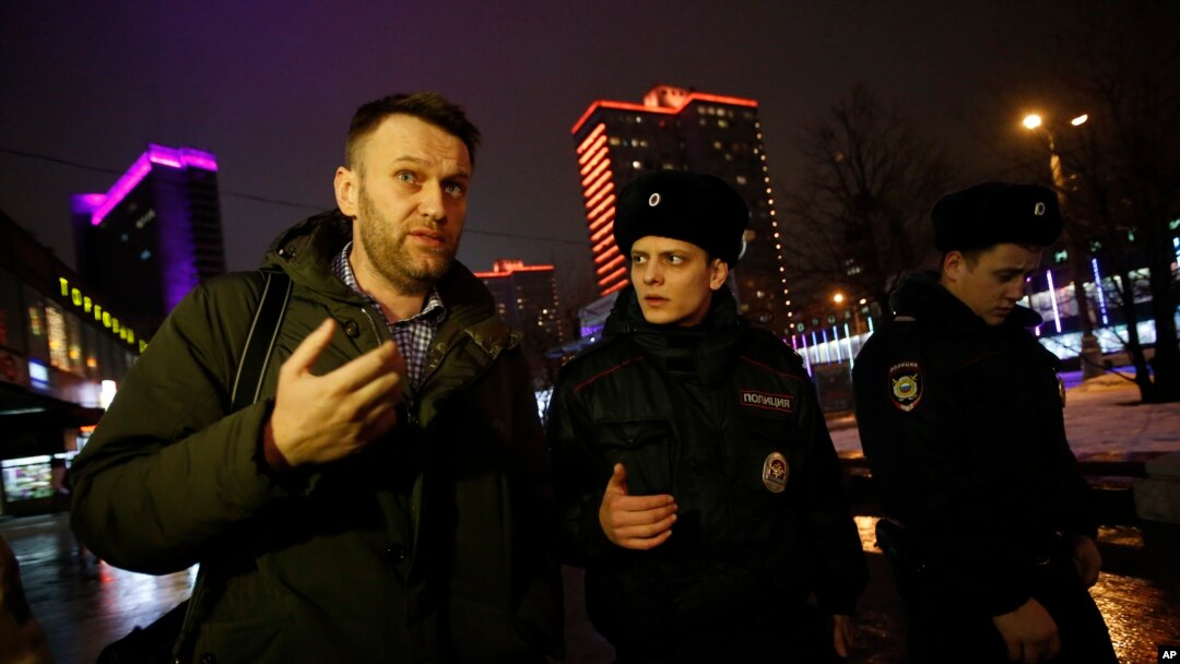 Russian opposition activist Alexei Navalny, left, is briefly detained by police officers after defying his house arrest to speak on Radio Ekho Moskvy in Moscow, Jan. 14, 2015.