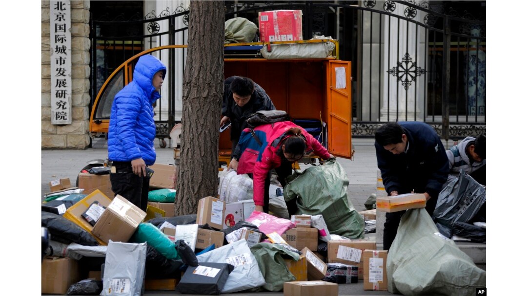 Delivery workers sort boxes of goods for their customers outside the capital city development academy in Beijing, China, Oct. 30, 2018. Surveys showed manufacturing in China weakened in December.