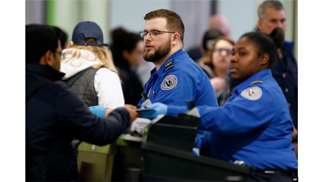 FILE - Transportation Security Administration officers work at a checkpoint at Logan International Airport in Boston, Jan. 5, 2019.