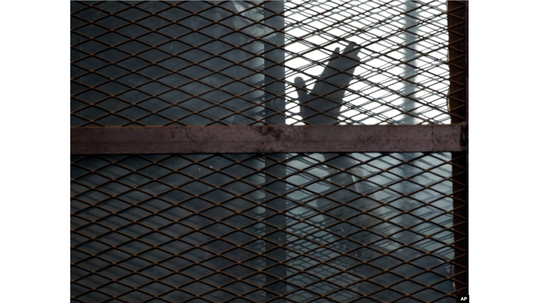 FILE - A defendant is seen caged in a courtroom in Torah prison, southern Cairo, Egypt, Aug. 22, 2015.