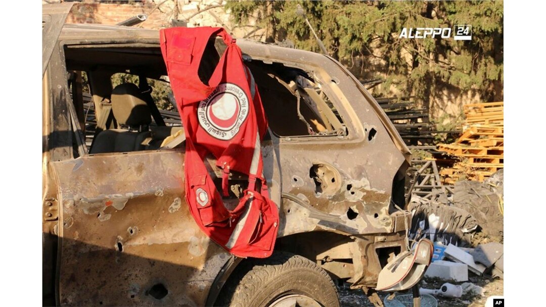 This image provided by the Syrian anti-government group Aleppo 24 news, shows a vest of the Syrian Arab Red Crescent hanging on a damaged vehicle, in Aleppo, Syria, Sept. 20, 2016.