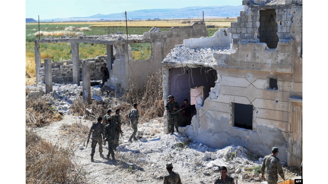 Syrian regime forces gather near a damaged building at the entrance of the town Kafr Nabouda, in the north of the Syrian Hama province, May 26, 2019.