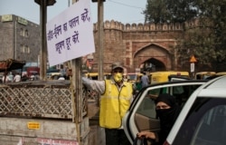 A volunteer from civil defence holds a placard with information regarding restrictions on private vehicles based on registration plates on a smoggy morning in New Delhi, India, November 4, 2019. REUTERS/Danish Siddiqui