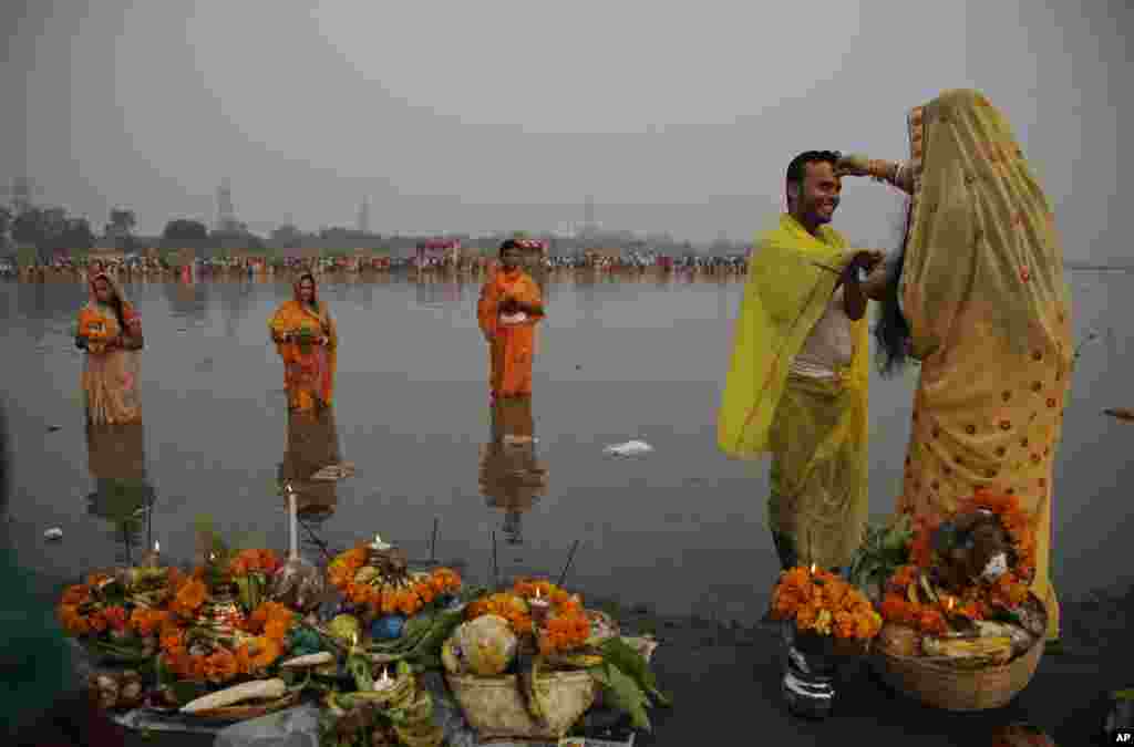 A Hindu devotee applies vermillion powder on the forehead of her husband as they perform rituals on the banks of the Yamuna River during Chhath Puja festival in New Delhi, India.