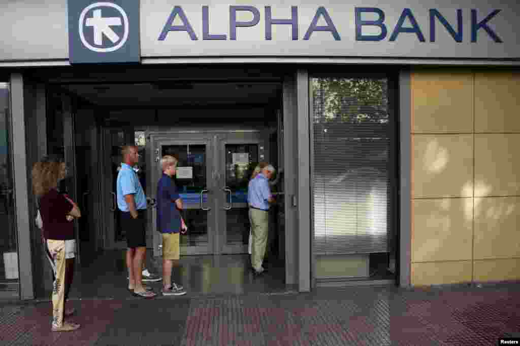 People line up at an ATM outside an Alpha Bank branch in Athens, July 15, 2015. 