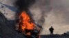 A man stands near his burning car along the road to a mountain pass, near the border between Nagorno-Karabakh and Armenia, on Sunday, Nov. 8, 2020. 