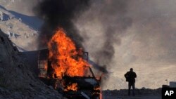 A man stands near his burning car along the road to a mountain pass, near the border between Nagorno-Karabakh and Armenia, on Sunday, Nov. 8, 2020. 