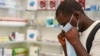 In this Feb. 6, 2020, photo, a man tries on a face mask at a pharmacy in Kitwe, Zambia.