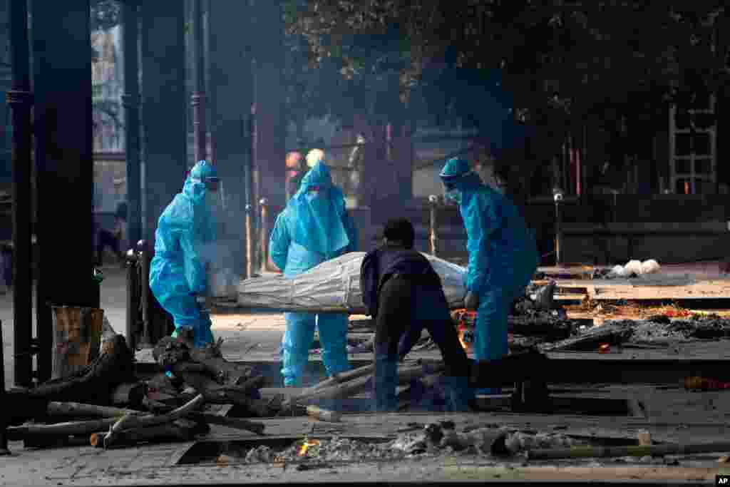 Health workers in personal protective equipment carry the body of a COVID-19 victim for cremation in New Delhi, India,.