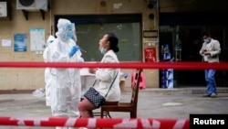 China -- A medical worker in protective suit conducts nucleic acid testings for residents at a residential compound in Wuhan, the Chinese city hit hardest by the coronavirus disease (COVID-19) outbreak, Hubei province, China May 15, 2020.