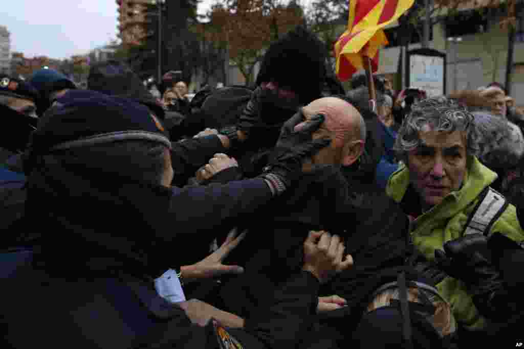 Catalan Mossos d'Esquadra officers scuffle with demonstrators as they cordon off the area around Lleida museum in the west of Catalonia, Spain. Police in Spain's northeastern Catalan city of Lleida have clashed with people protesting a judicial ruling ordering the city's museum to return 44 pieces of religious art to the neighboring regional government of Aragon.