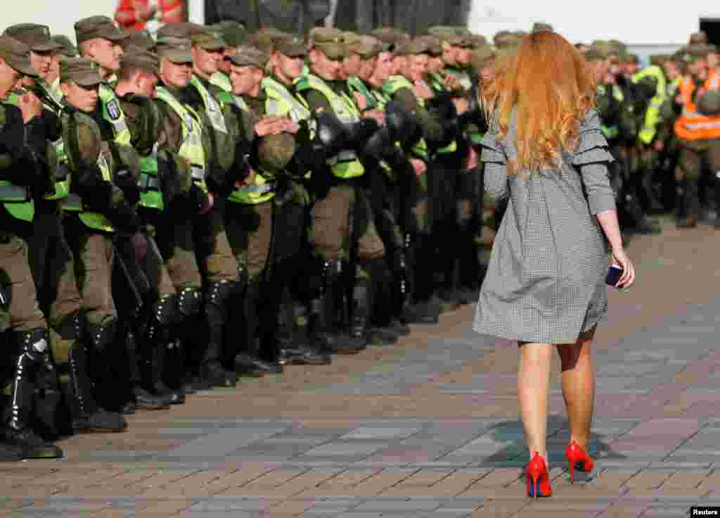 A woman walks past servicemen of the National Guard in front of Ukrainian Parliament during a opposition rally in Kyiv.