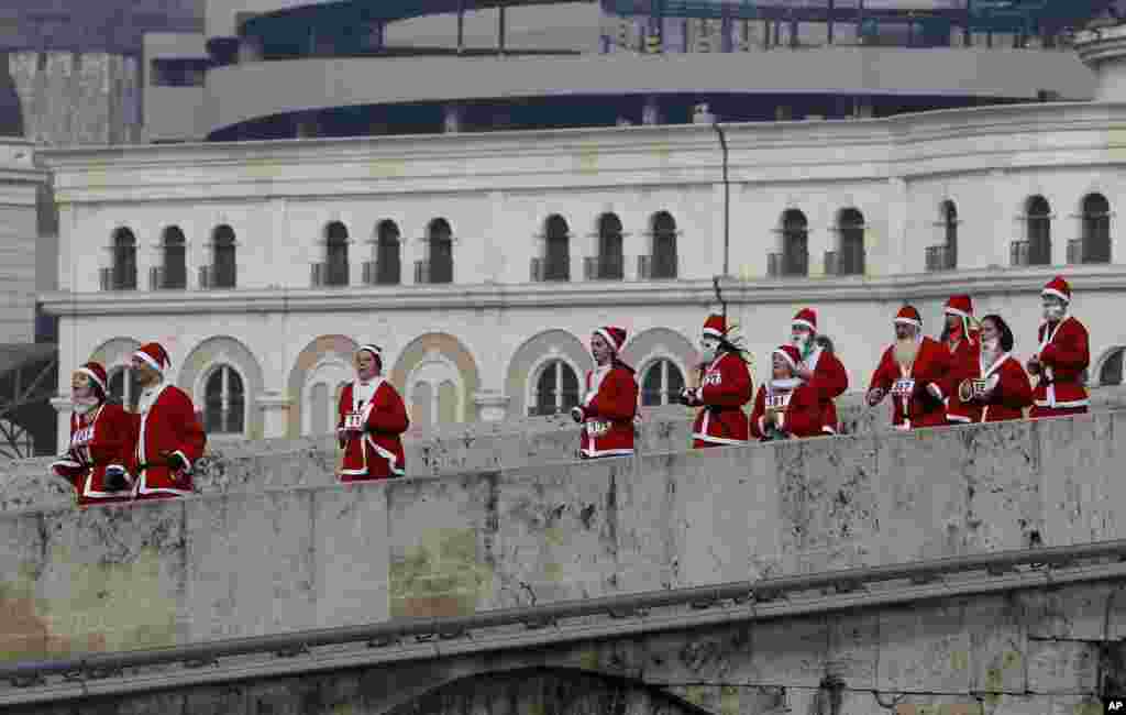 People dressed in Santa Claus costumes run across a bridge during a Santa Claus Race in Macedonia's capital Skopje, Dec. 25, 2016.