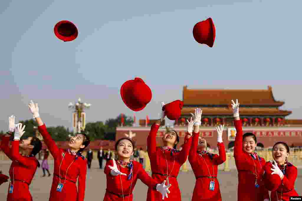 Ushers throw their hats in the air as they pose for photographers at the Tiananmen Square before the closing session of the 19th National Congress of the Communist Party of China, in Beijing.