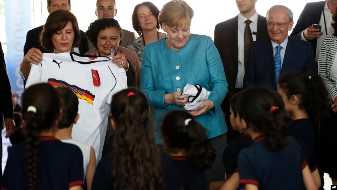 German Chancellor Angela Merkel (C) distributes shirts of the German national soccer team to Lebanese and Syrian displaced students studying together, during her visit to a Lebanese public school, in Beirut, Lebanon, June 22, 2018.