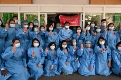 Medical workers wearing red ribbons pose during a protest against the coup that ousted elected leader Aung San Suu Kyi, in Yangon General Hospital in Yangon, Myanmar, Feb. 3, 2021.