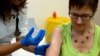 FILE - Dr. Felicity Hartnell, an Oxford University researcher, injects former nurse Ruth Atkins, a volunteer in an experimental Ebola vaccine program, in Oxford, England, Sept. 17, 2014.