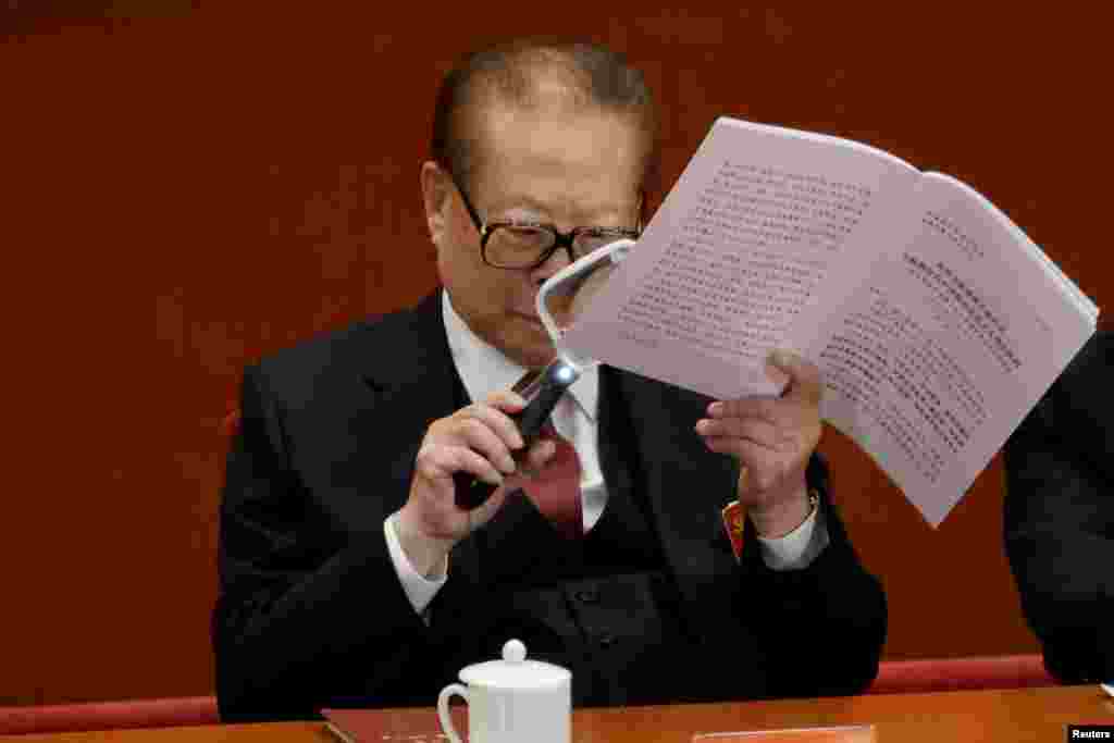 Former Chinese President Jiang Zemin uses a magnifier as he reads Chinese President Xi Jinping's report during the opening of the 19th National Congress of the Communist Party of China at the Great Hall of the People in Beijing.