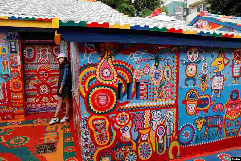 A visitor poses for a photo at rainbow village, a former military dependents' village which has become a tourist attraction in Taichung, Taiwan.