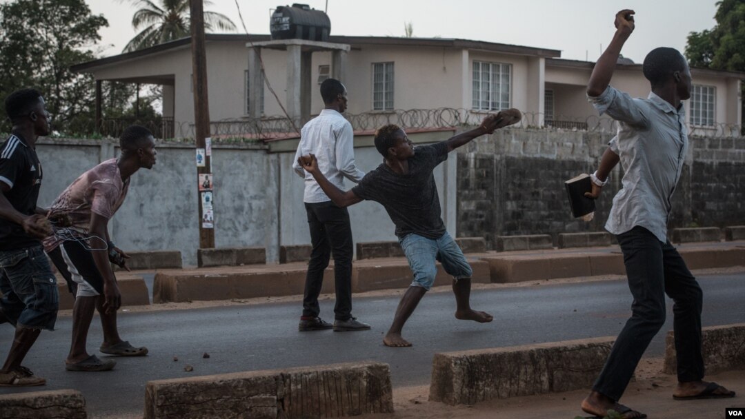 Supporters of the opposition Sierra Leone People's Party throw rocks at police following an alleged incident at party headquarters in Freetown's Goderich neighborhood, March 7, 2018. (J. Patinkin/VOA)