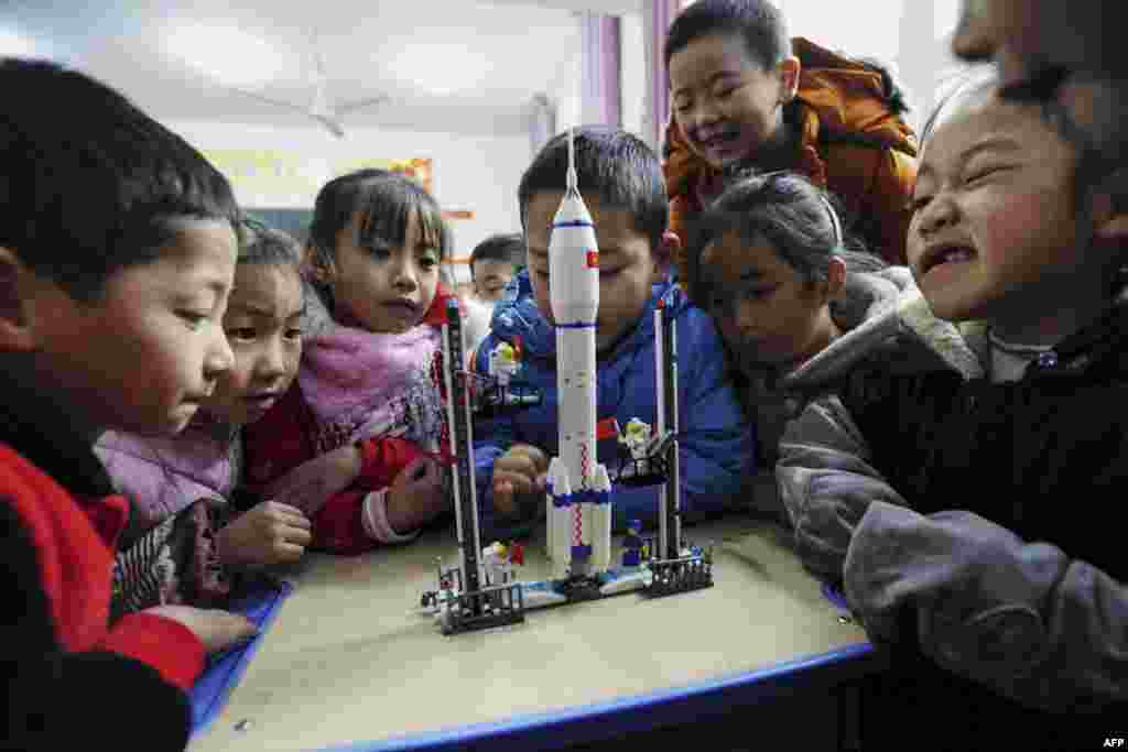 Children look at a model of the Longmarch rocket during an aerospace education lesson at a primary school in Yunyang county in southwestern China's Chongqing.