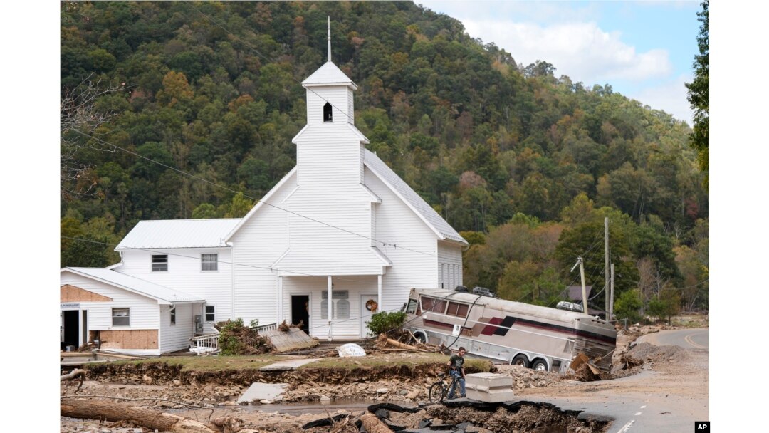 In the aftermath of Hurricane Helene, Dominick Gucciardo walks by a bus pushed by floodwaters against Laurel Branch Baptist Church in Pensacola, North Carolina, Oct. 3, 2024.