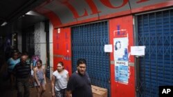Pedestrians walk past the Lion's storefront temporarily closed by authorities for selling transgender dolls, in Ciudad del Este, Paraguay, Jan. 10, 2018.