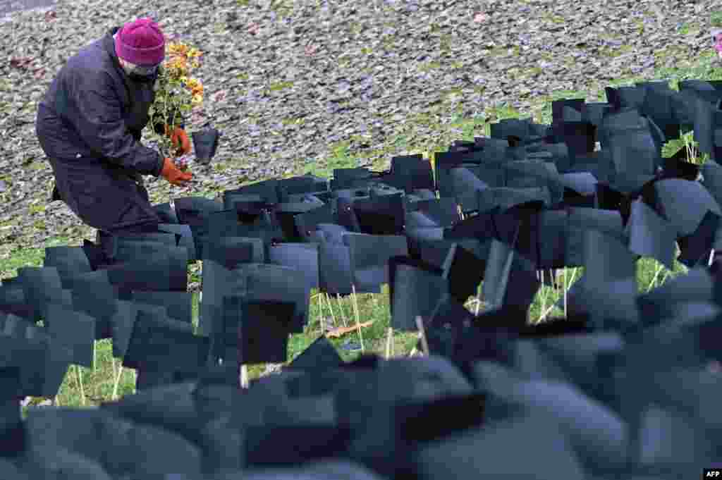 An elderly woman places flowers in front of several thousand black paper flags set up at the "Bikas" (Bull) Park in Budapest in tribute to the people who died during the novel coronavirus pandemic, as the number of reported deaths surpassed 6,000 in Hunga
